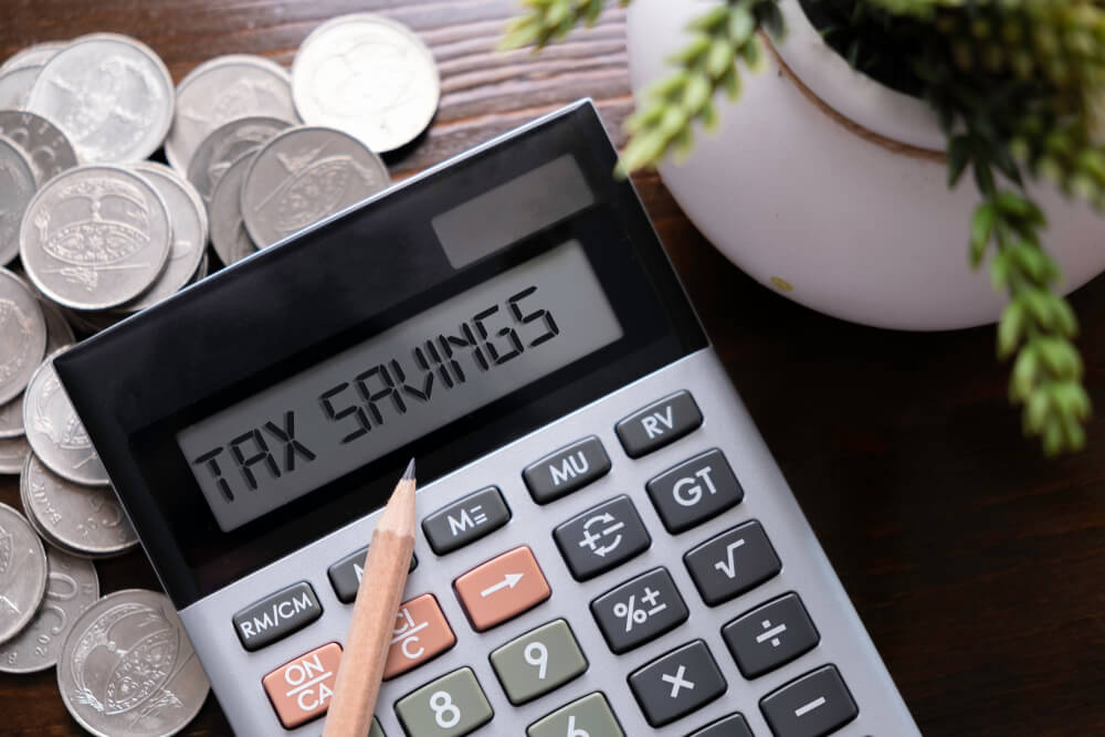 tax savings displaying on the calculator with pencil, pot and stack of coins