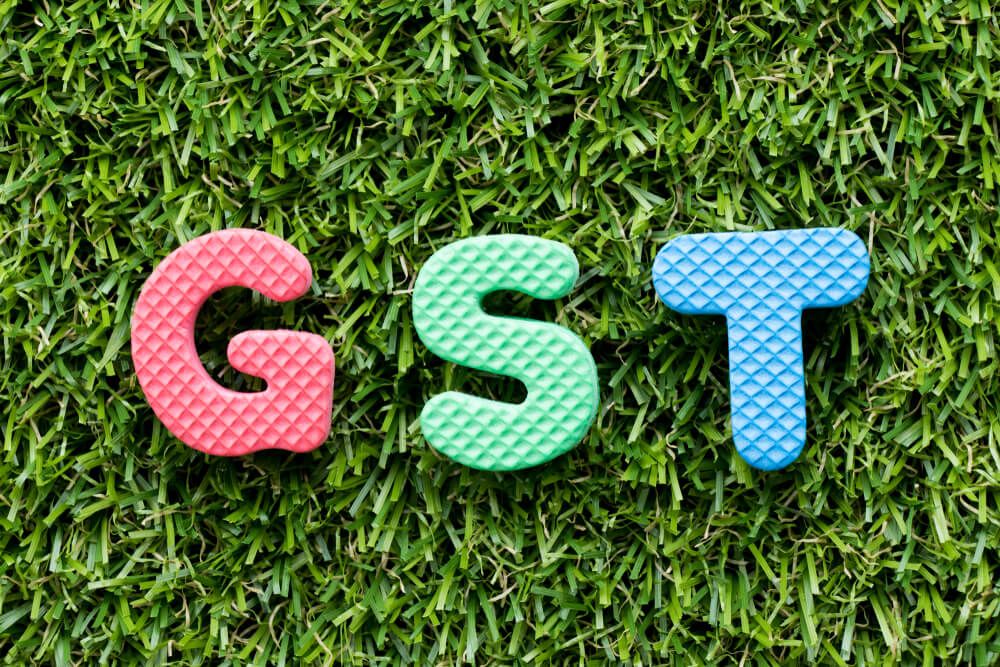 Colour alphabet letter in word GST on artificial green grass background